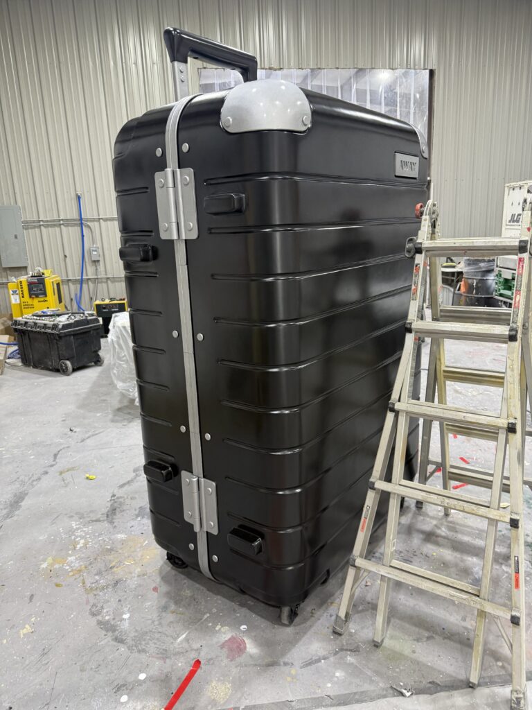 An 8-foot Away suitcase foam sculpture dwarfing a ladder at Smash Design studios
